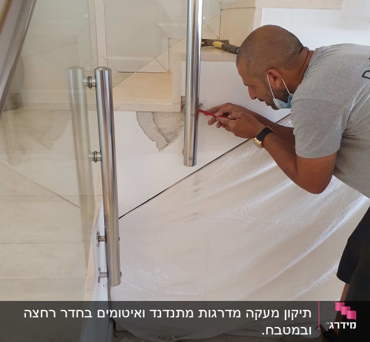 אדם מתקין מעקה מתכת במדרגות עם כלי עבודה